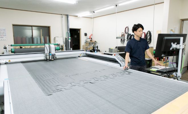 大きな裁断機を使う工房スタッフの写真