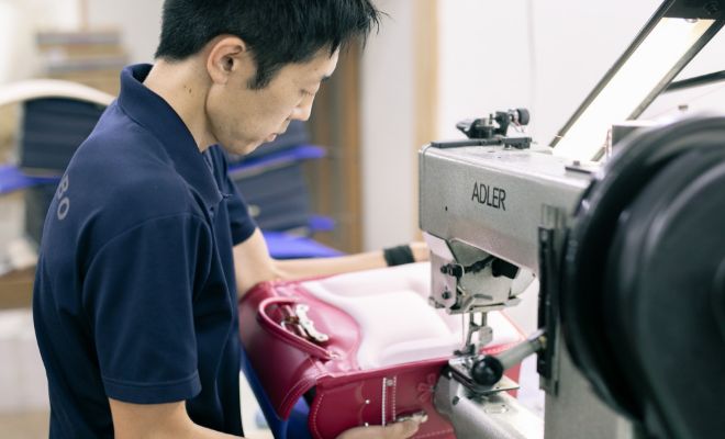 ランドセルにミシンをかける工房スタッフの写真