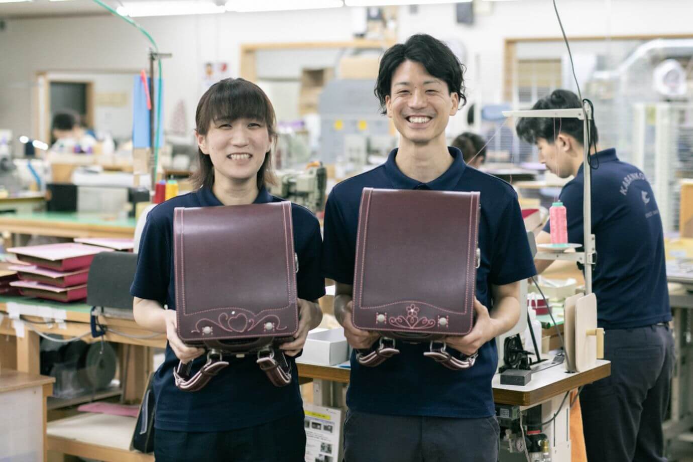 笑顔でランドセルを持つスタッフ2人の写真
