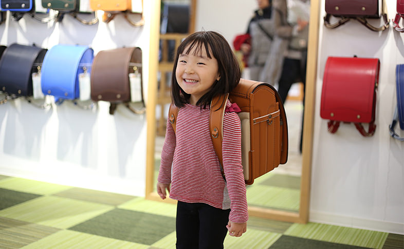 お気に入りのキャメル色のランドセルを背負って、笑顔で希望を伝える女の子