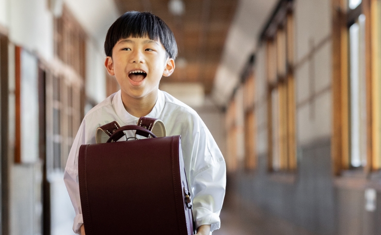 ワイン色のランドセルを楽しそうに抱える男の子