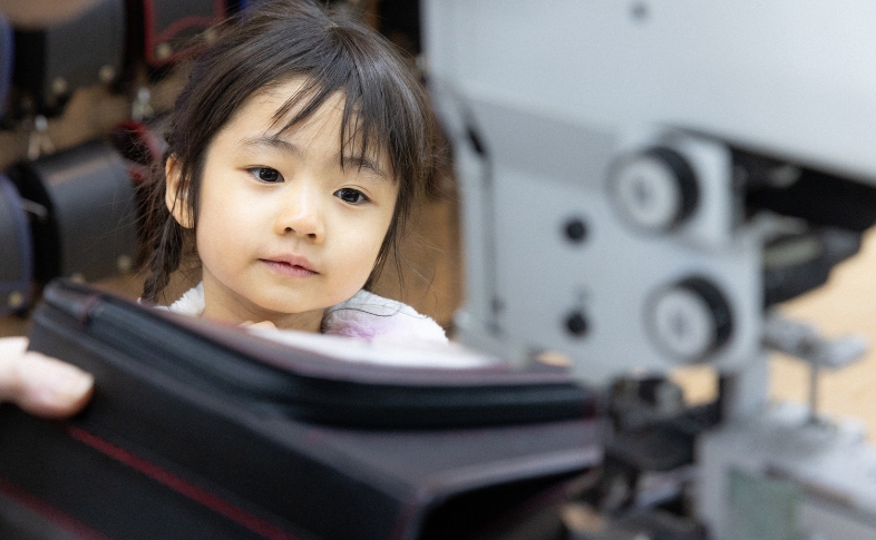 ランドセルづくりをみつめる少女。工房見学の様子