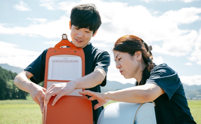 2人の職人がランドセルを覗き込んでいる