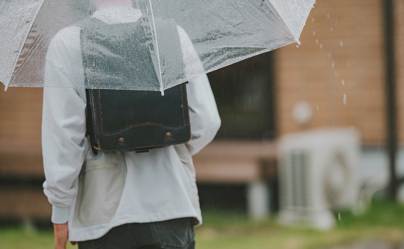 雨の通学路と、ランドセルを背負った少年